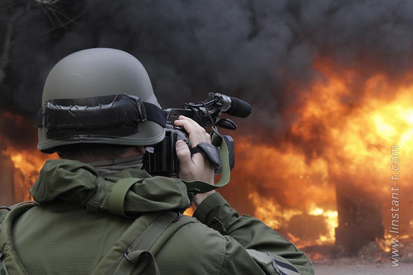 Un homme en tenue militaire avec un casque Kevlar film l'incendie de l'hôtel Ibis